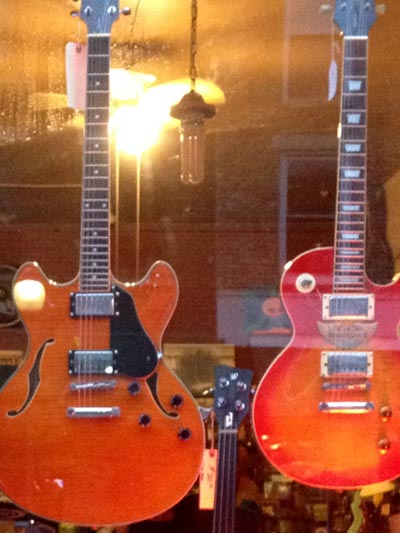 photo of two electric guitars in window
